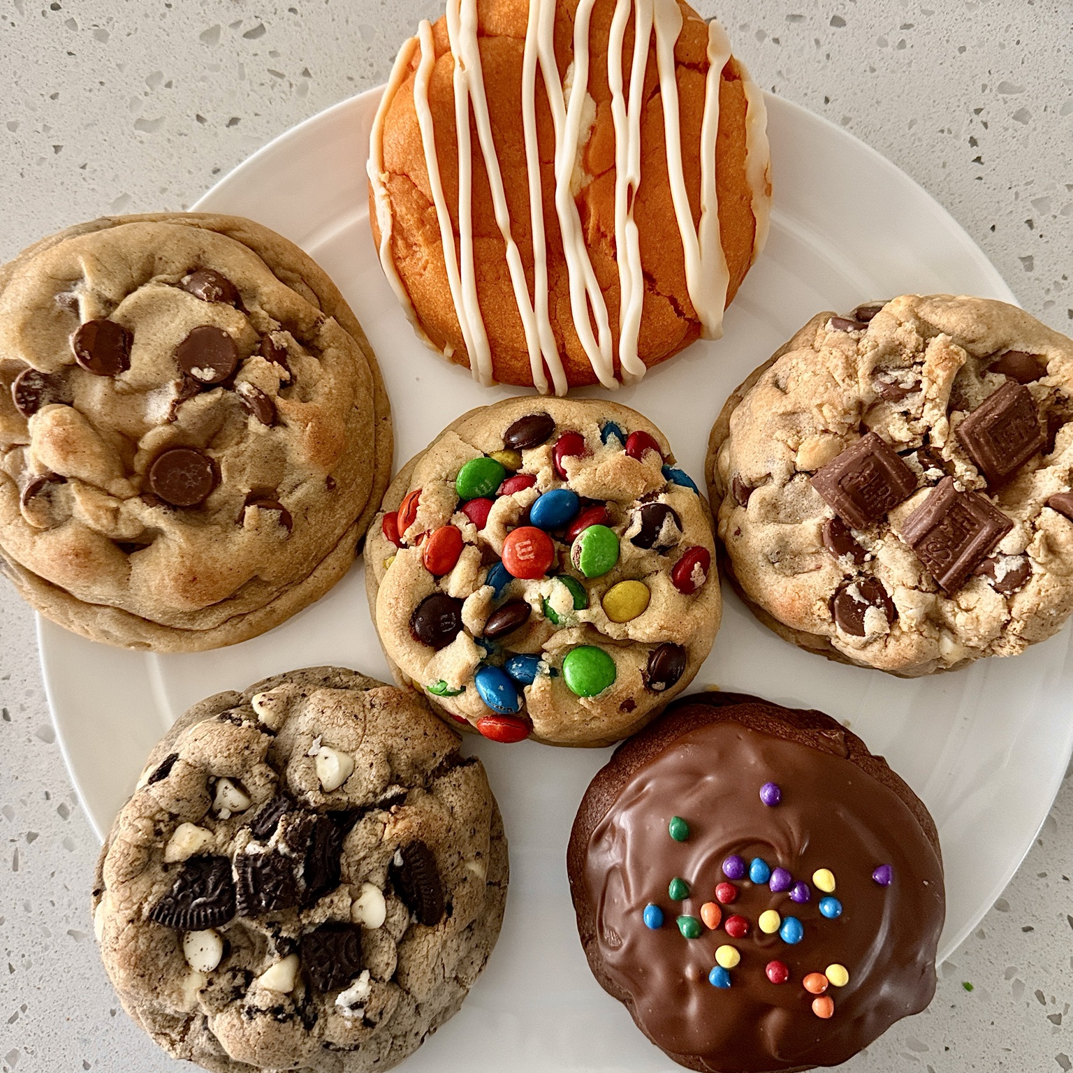 Six different LadyBug’s Bakery cookies arranged on a white plate